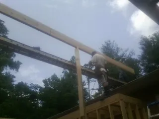 Carpenter setting a ridge beam over a new addition frame — Ice Dam Removal by Roofing Brothers in Dibble