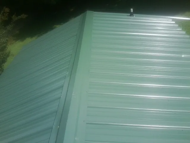 New green metal panels meeting at the ridge of a roof — Flat Roof Repair work by our crew in Dibble