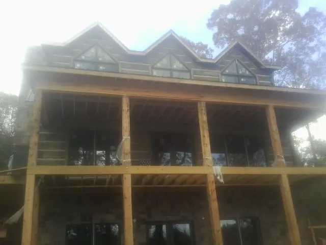 Dormers and porch framing on a large log home under construction — Roof Coating work by our crew in Dibble