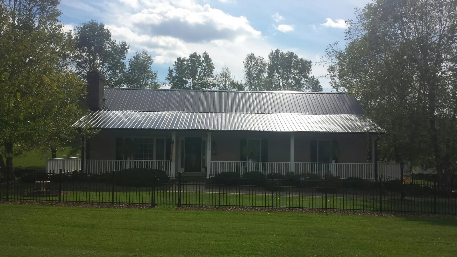 Gray metal roof on a brick ranch with a full width front porch — Gutter Guard Installation work by our crew in Dibble