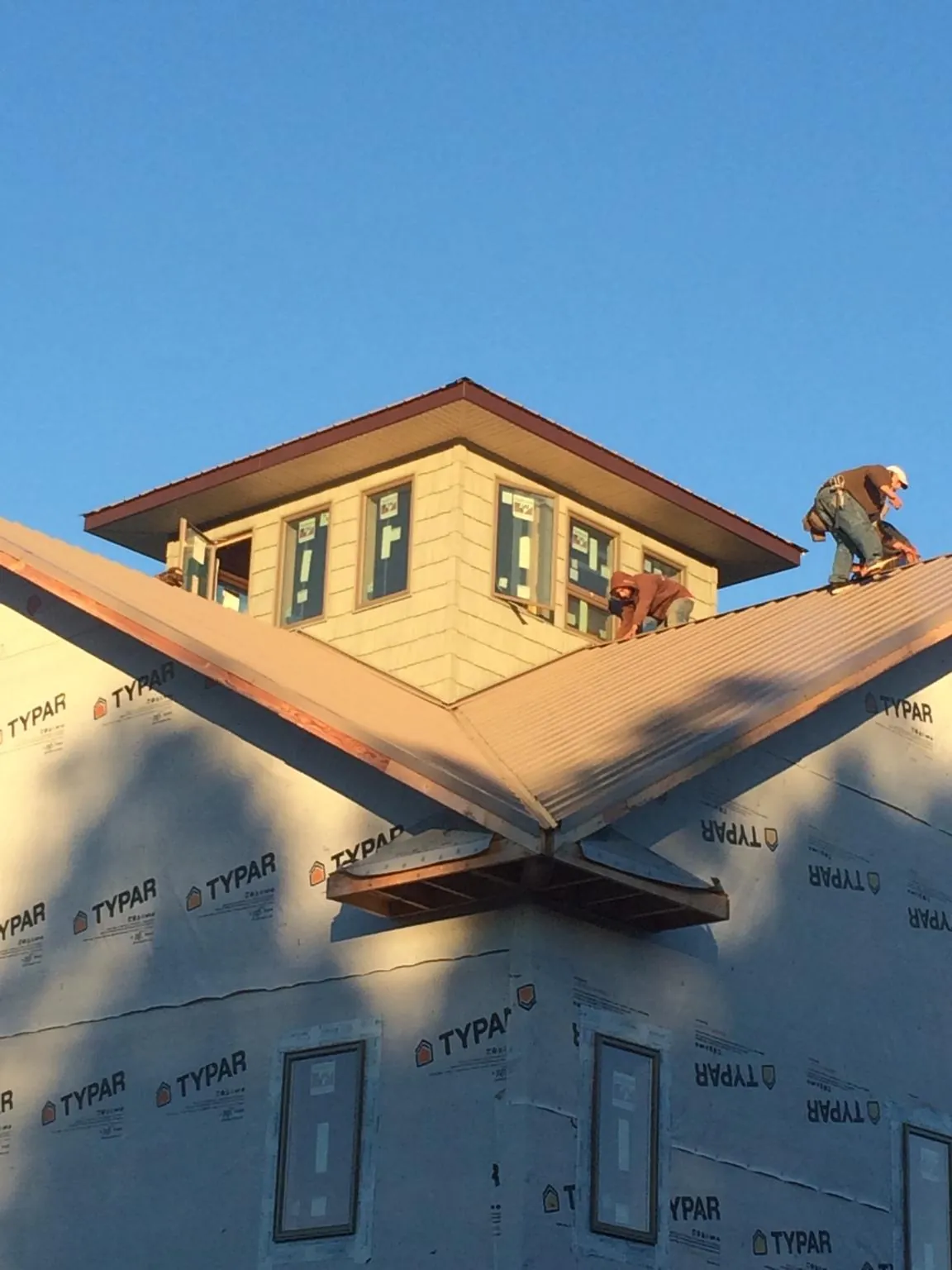 Roofers working around a rooftop cupola on a new metal roof at sunset — Roof Waterproofing in Dibble by Roofing Brothers